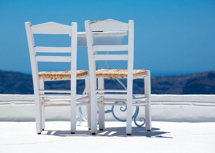 Two white chairs and a blurred panoramic view of the hills of santorini, Greece 2013.